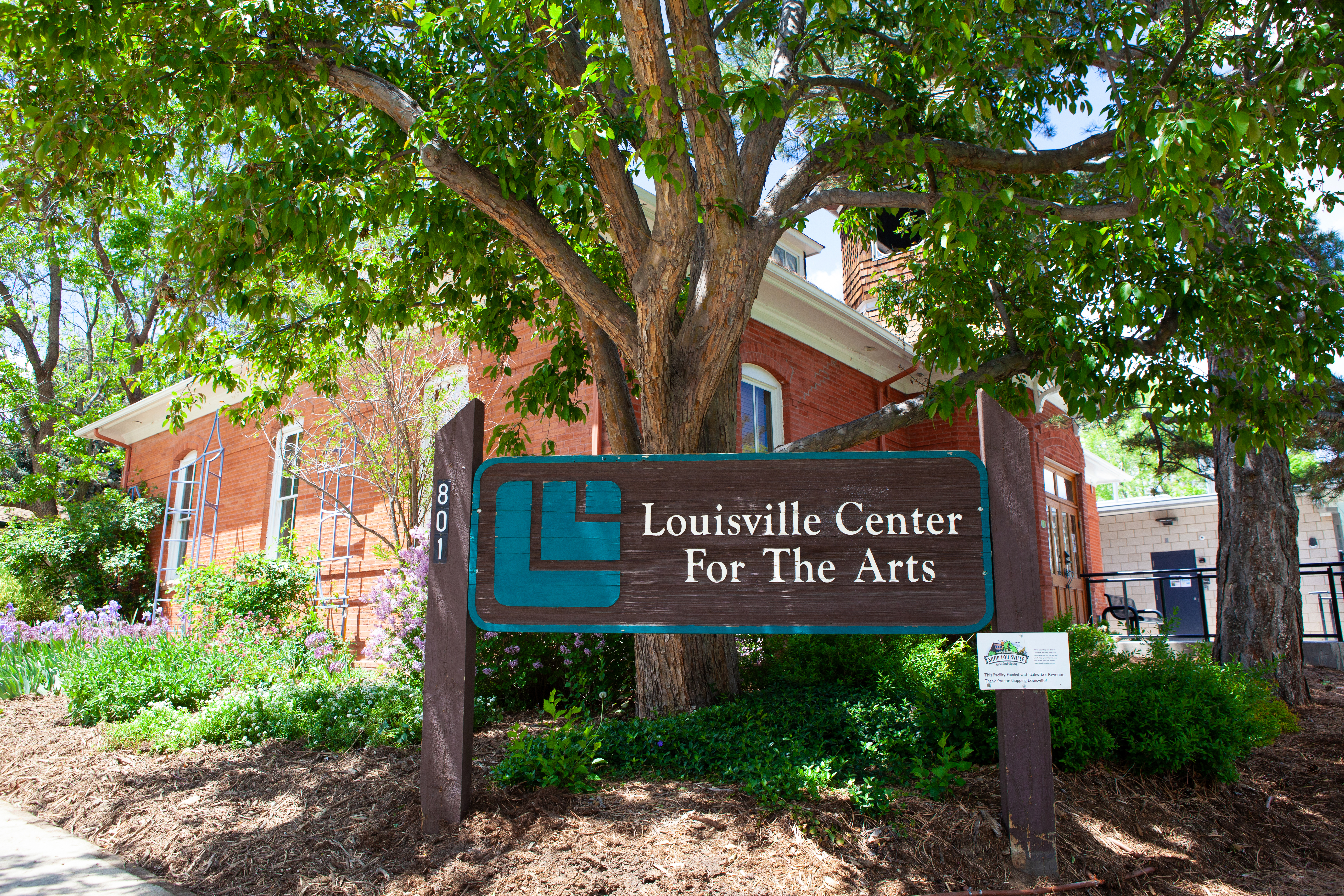 A sign reading City of Louisville Center for the Arts in front of a red brick building.
