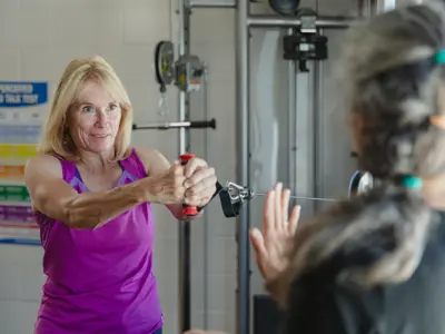 Fitness instructor guiding an older adult through an exercise.
