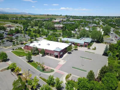 A rendering of a corporate building with parking lot and trees.