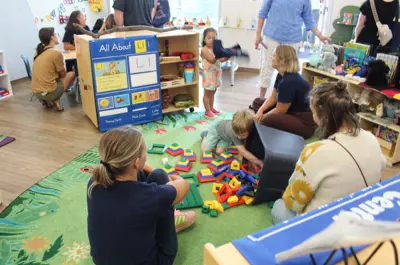 Children and adults play in a colorful preschool classroom.