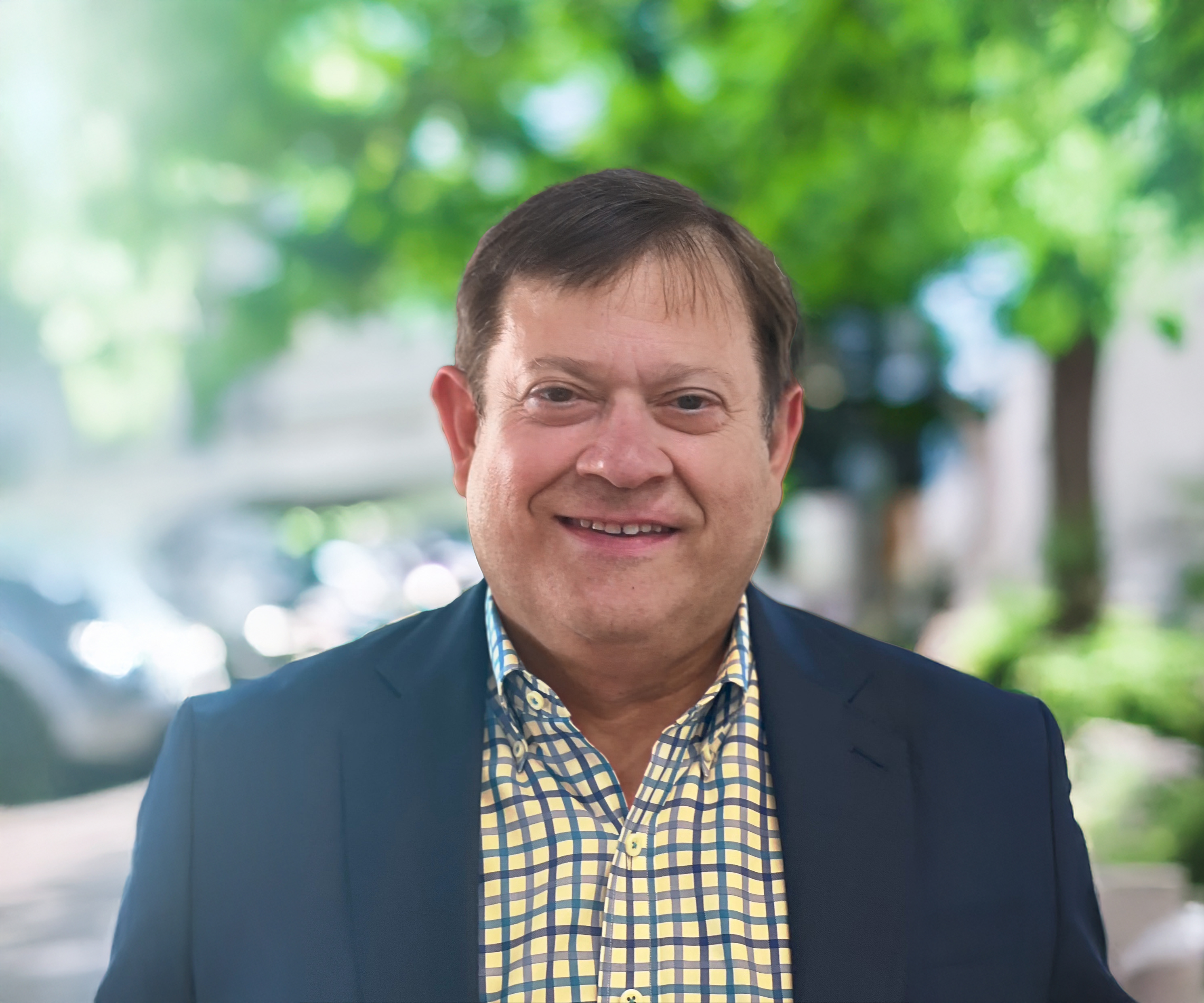 Headshot of a man wearing a checked shirt and jacket.