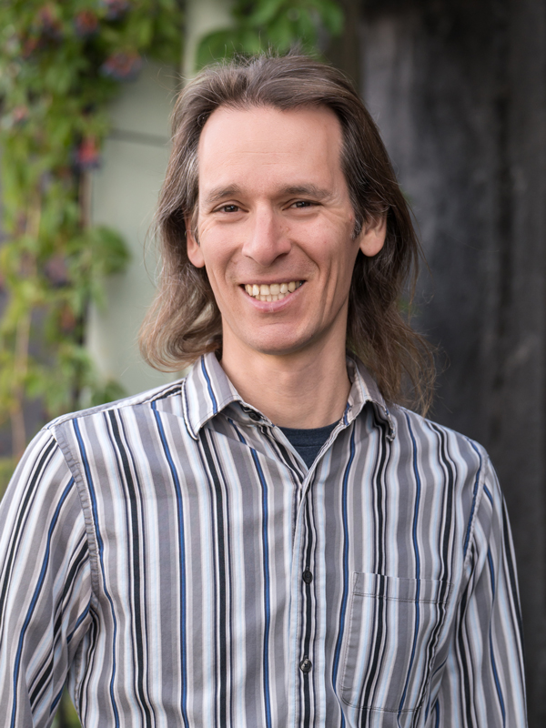Headshot of a man wearing a striped shirt outside.