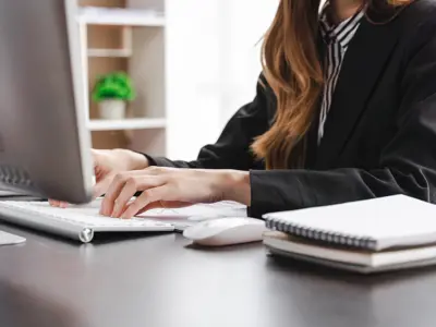 A woman at a desk typing on a computer.