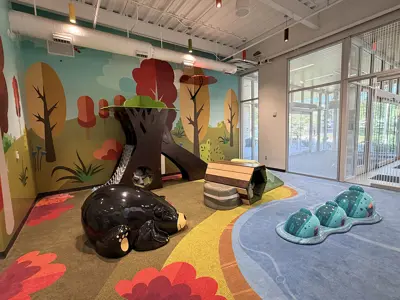 Children’s playroom with colorful mats, toys, and wall art.