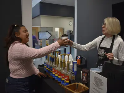 A volunteer handing a latte to a patron