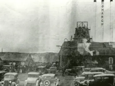A black and white photo showing cars and a building.
