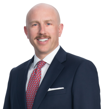 Headshot of a man wearing a black suit in front of a light background.